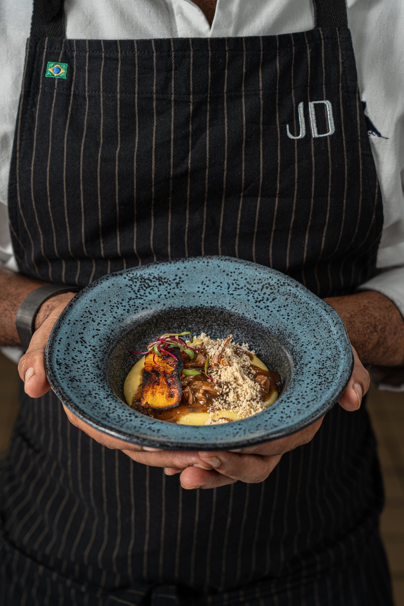 Chef do ALTO apresentando um prato autoral servido em louça artesanal